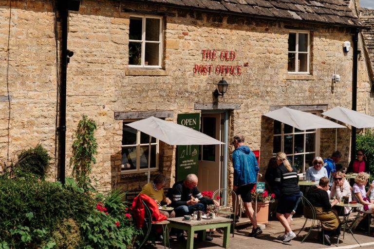 Cyclists enter the Old Post Office, Cotswolds